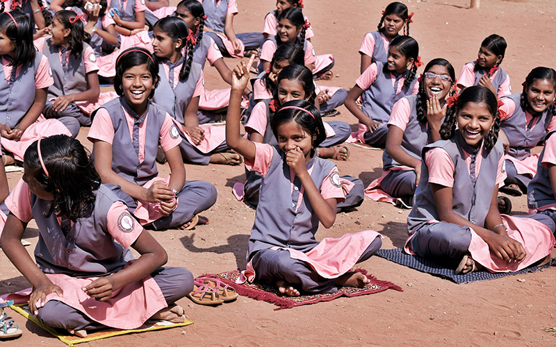 Group of smiling school girls sitting outdoors